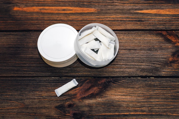 Two snus cans and pouches on a dark wooden surface